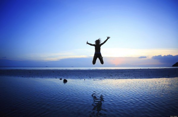 Silhouette of woman jumping high in the air at beach.
